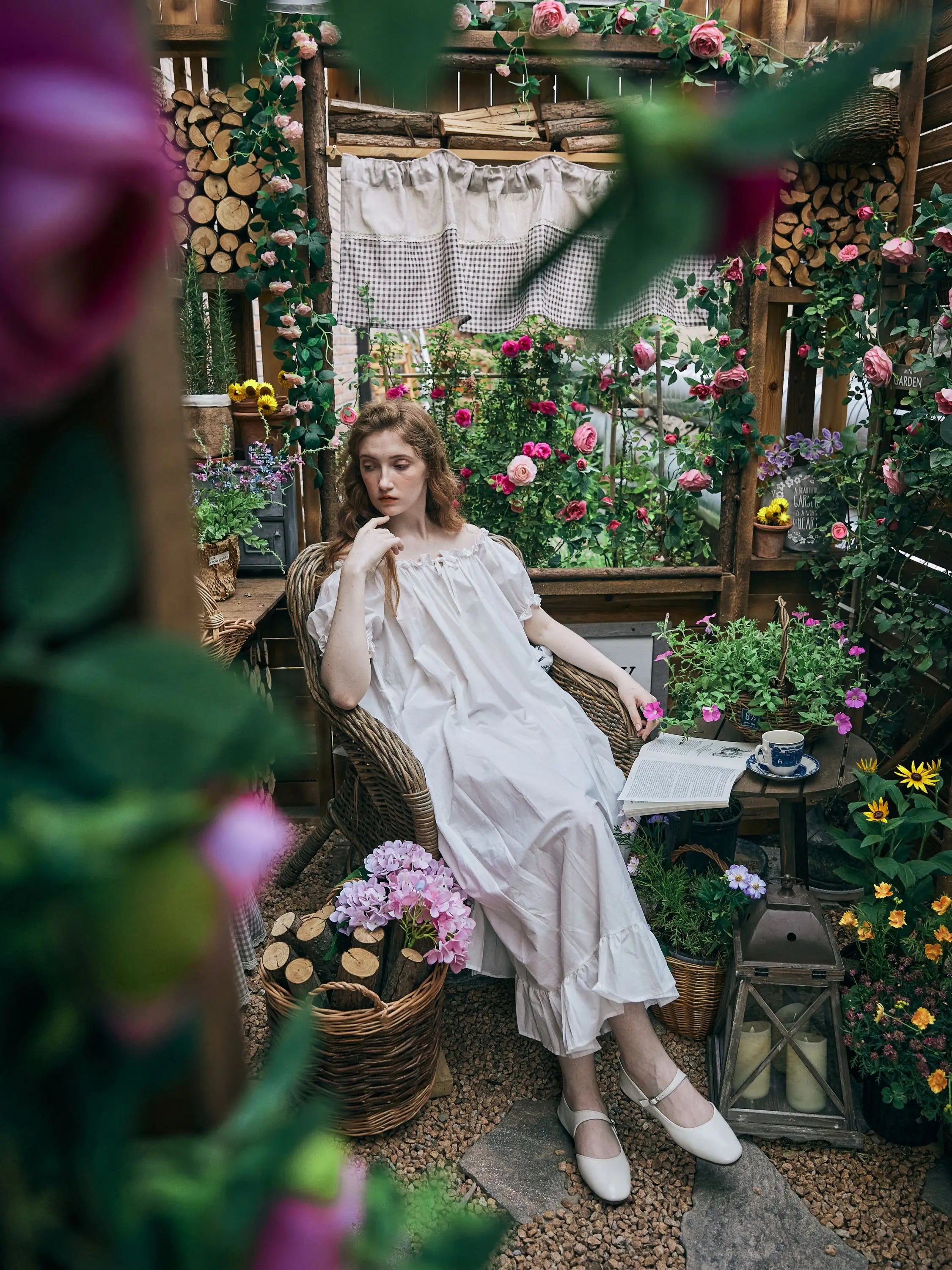 Woman relaxing in a garden chair wearing a long white cotton nightgown, showcasing the modest Victorian design and ruffled hem.