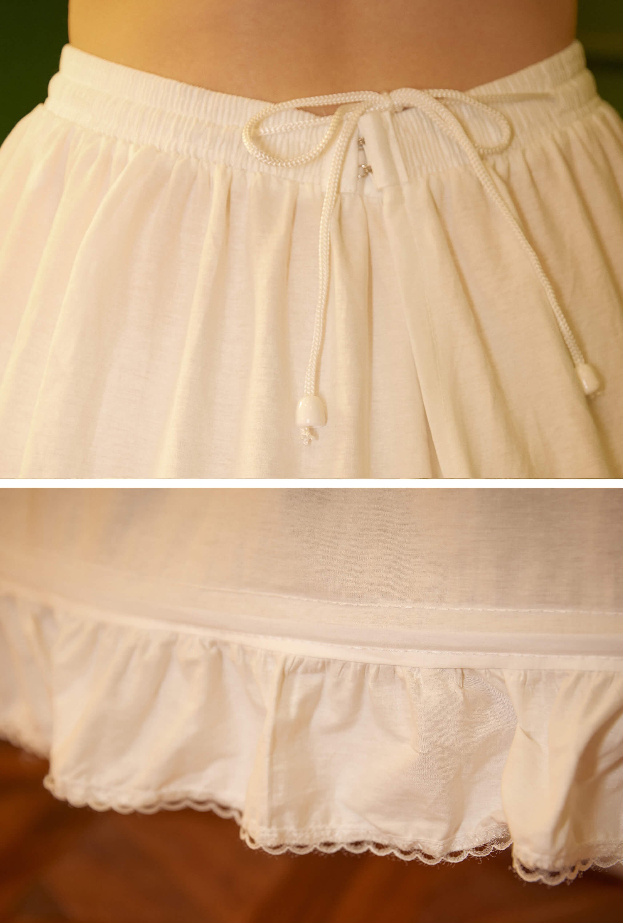 Close-up detail of the adjustable waistband on the ivory cotton hoop petticoat, featuring the elastic band, button hooks, and drawstring for a secure fit.