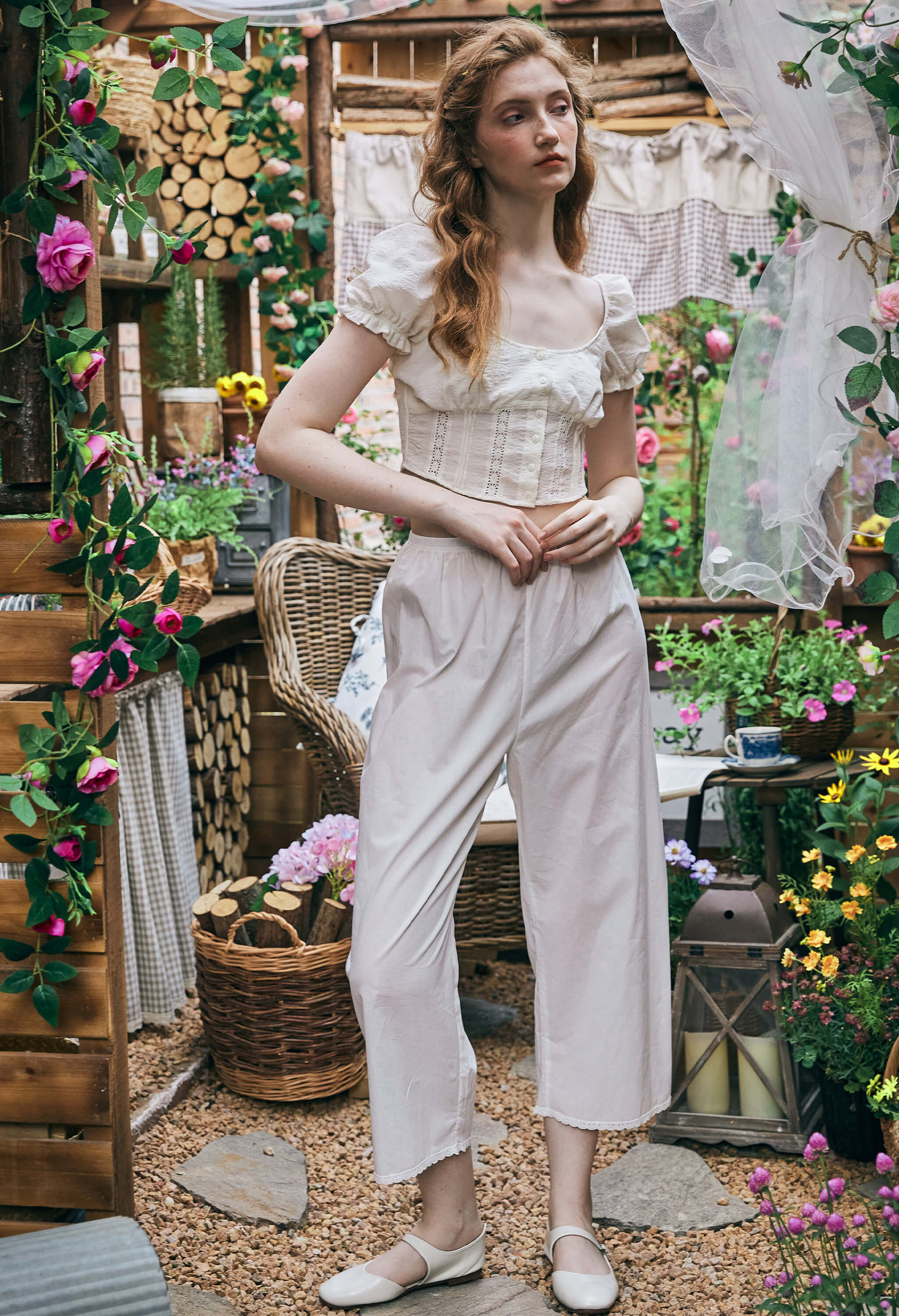 Full body shot of a woman in a garden wearing Sueasyretro Pajamas Pants, elegant white cotton Pettipants with a crop top.