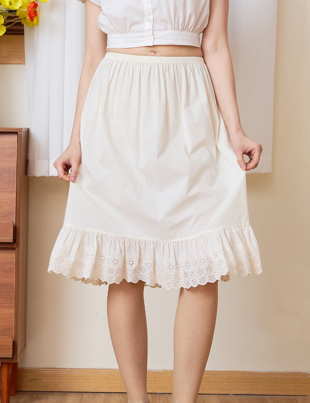 Close-up of a cream cotton petticoat highlighting exquisite English checkerboard eyelet lace and winding floral vines.