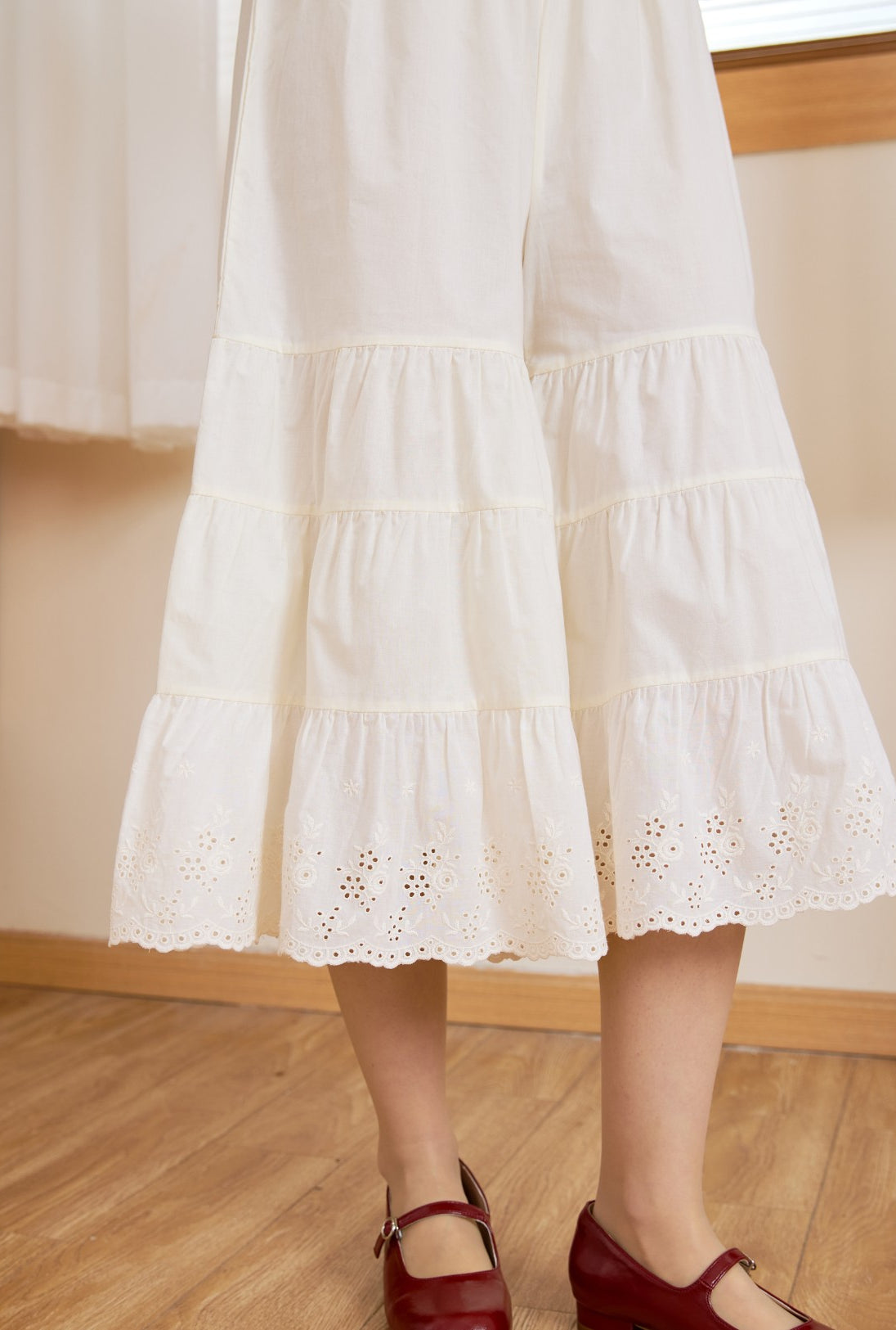 Close-up of the delicate floral eyelet lace hem on these cream cotton bloomers, showing exquisite vintage craftsmanship.