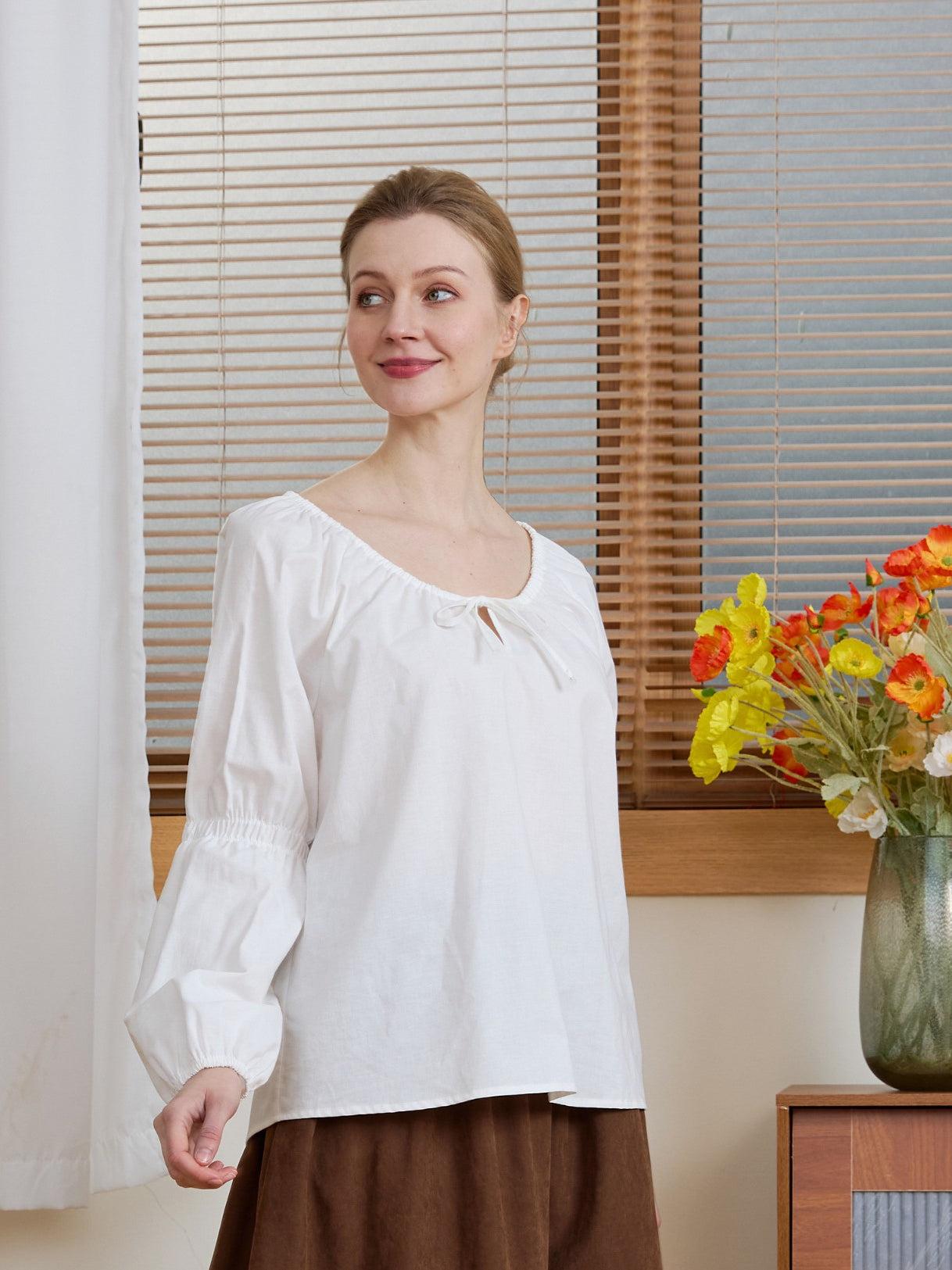 Model wearing an Ivory Renaissance Cotton Blouse, looking aside to highlight the relaxed fit and gathered sleeves.
