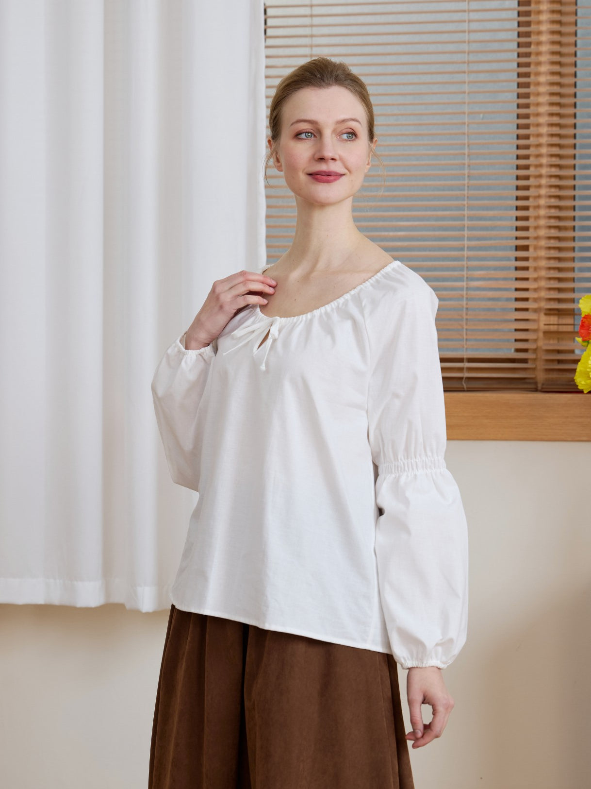 Half-body shot of the Ivory Renaissance Cotton Blouse, highlighting the peasant-style neckline and gathered cuffs.