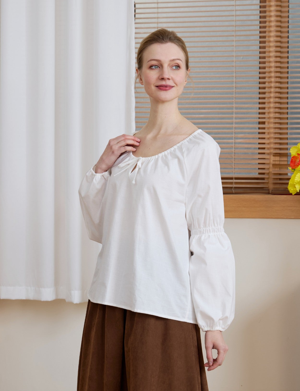 Half-body shot of the Ivory Renaissance Cotton Blouse, highlighting the peasant-style neckline and gathered cuffs.