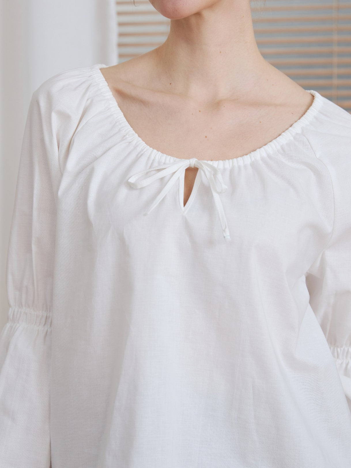 Close-up detail of the drawstring tie neckline on the Ivory Renaissance Cotton Blouse, showing the fabric texture.