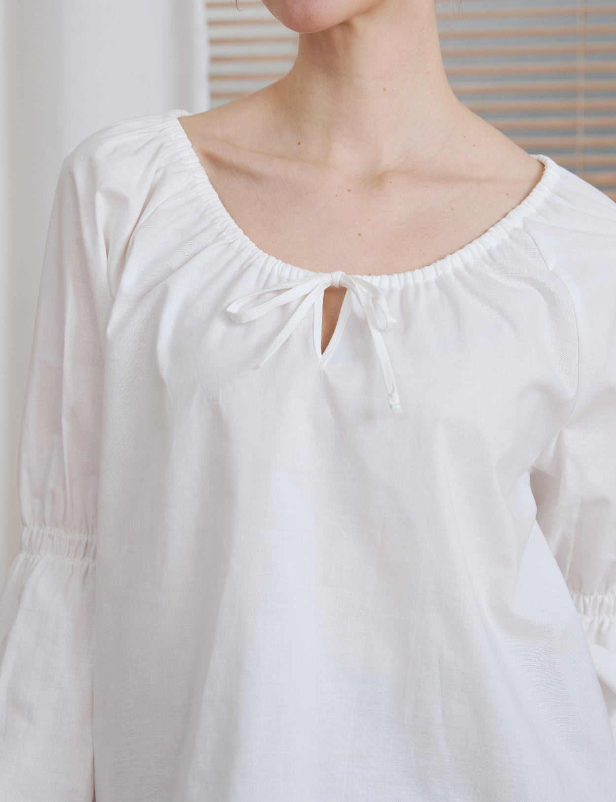 Close-up detail of the drawstring tie neckline on the Ivory Renaissance Cotton Blouse, showing the fabric texture.