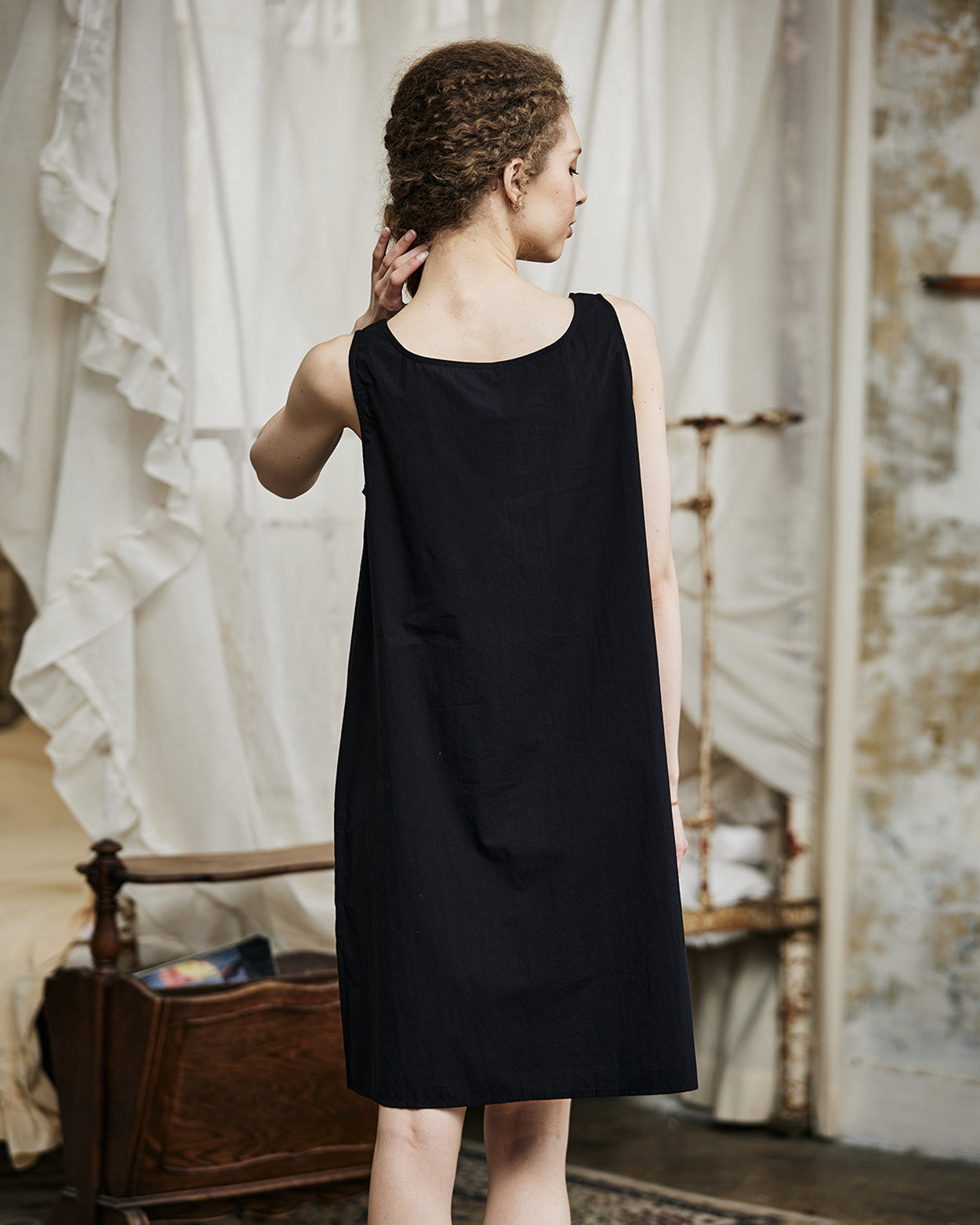 Women's black cotton full slip with wide straps, showing modesty panel and knee-length design - back view