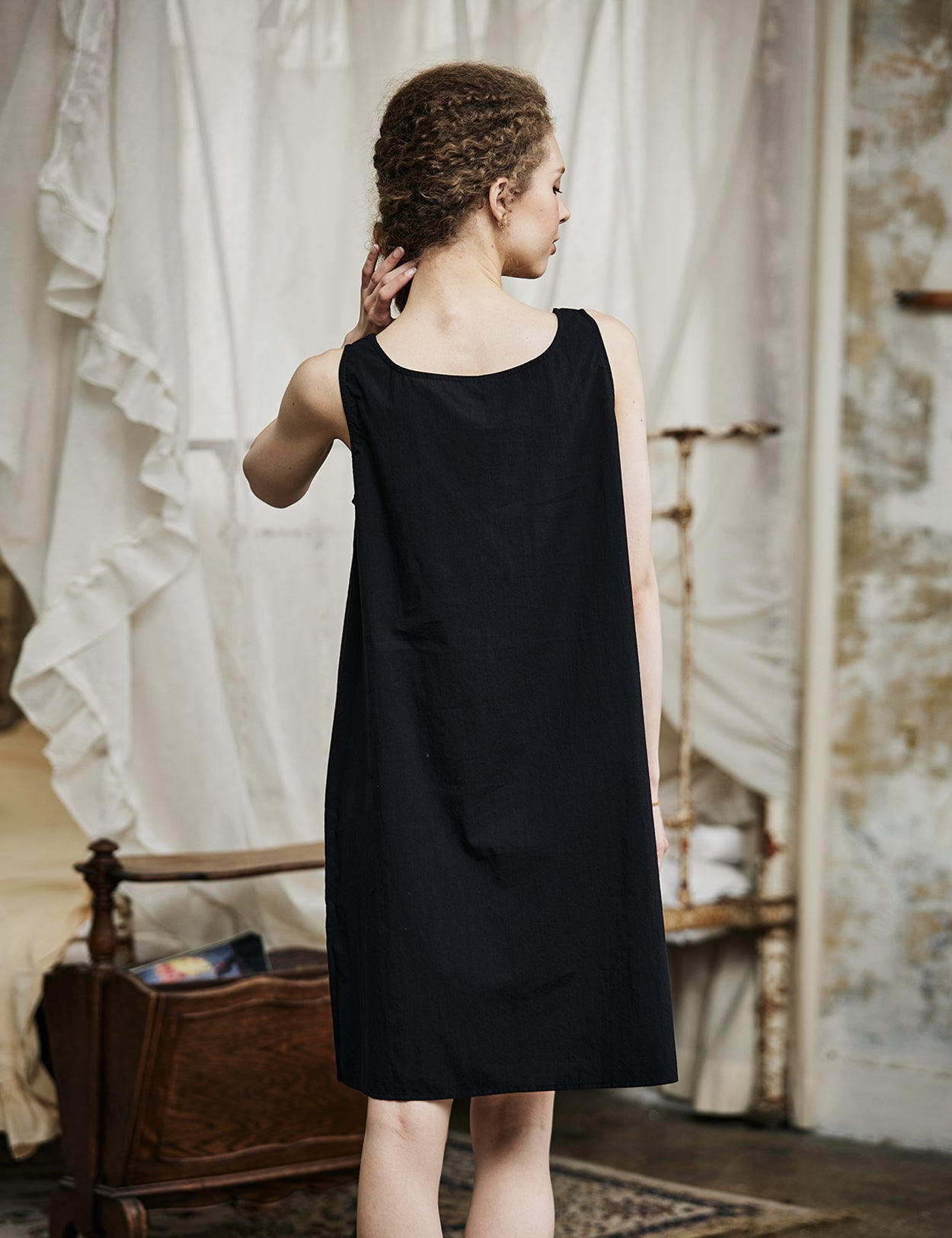 Women's black cotton full slip with wide straps, showing modesty panel and knee-length design - back view