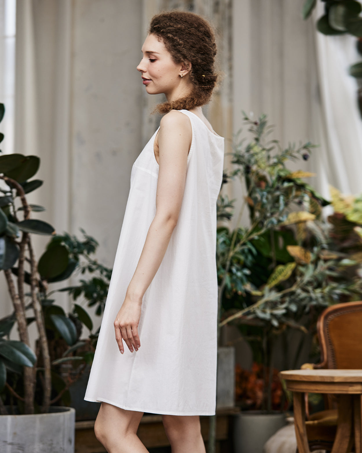 Women's white cotton full slip with wide straps, showing modesty panel and knee-length design - side view