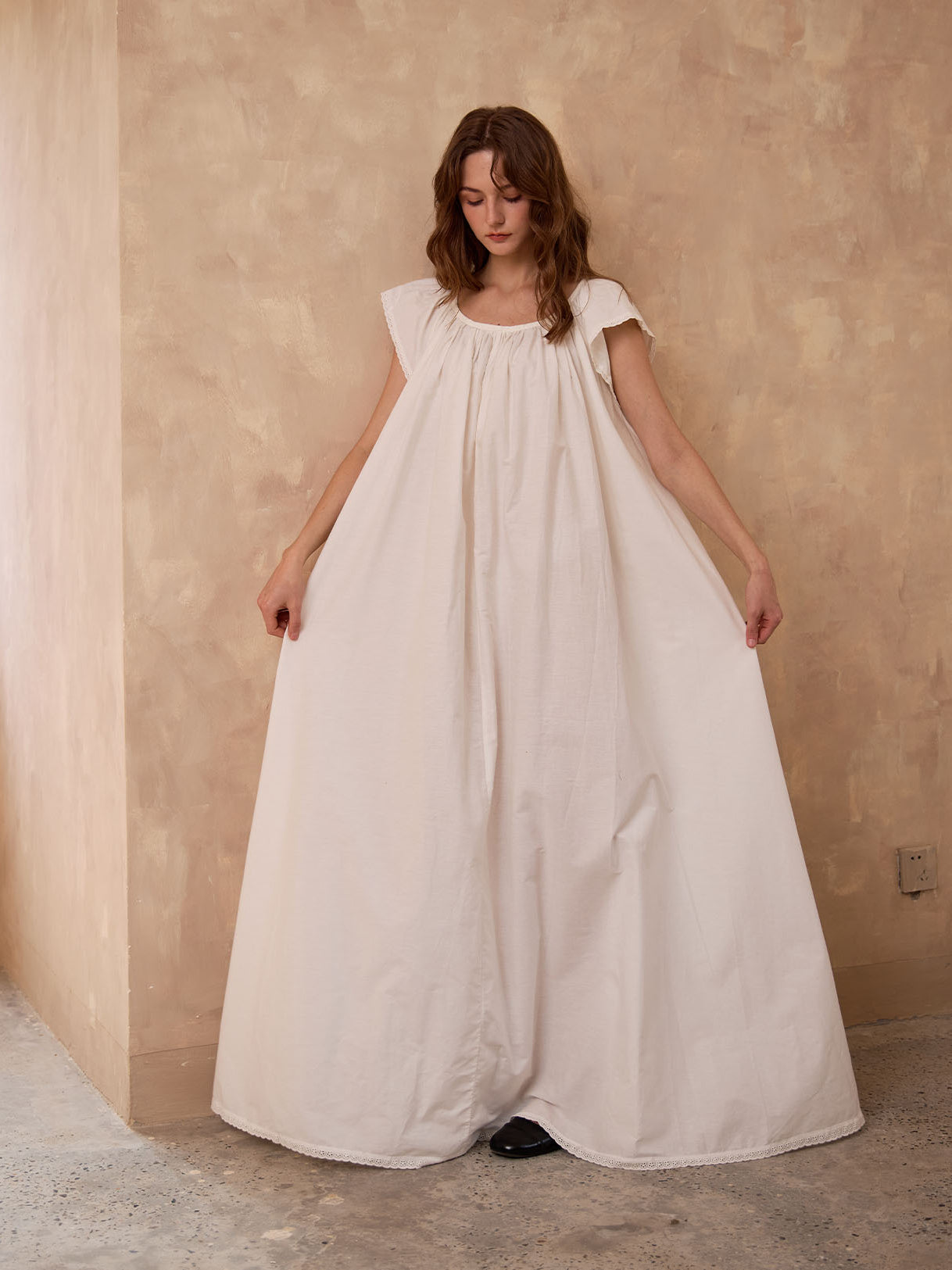 Sueasyretro floor-length ivory Victorian nightgown. Woman holding the voluminous 100% cotton skirt with lace hemline.