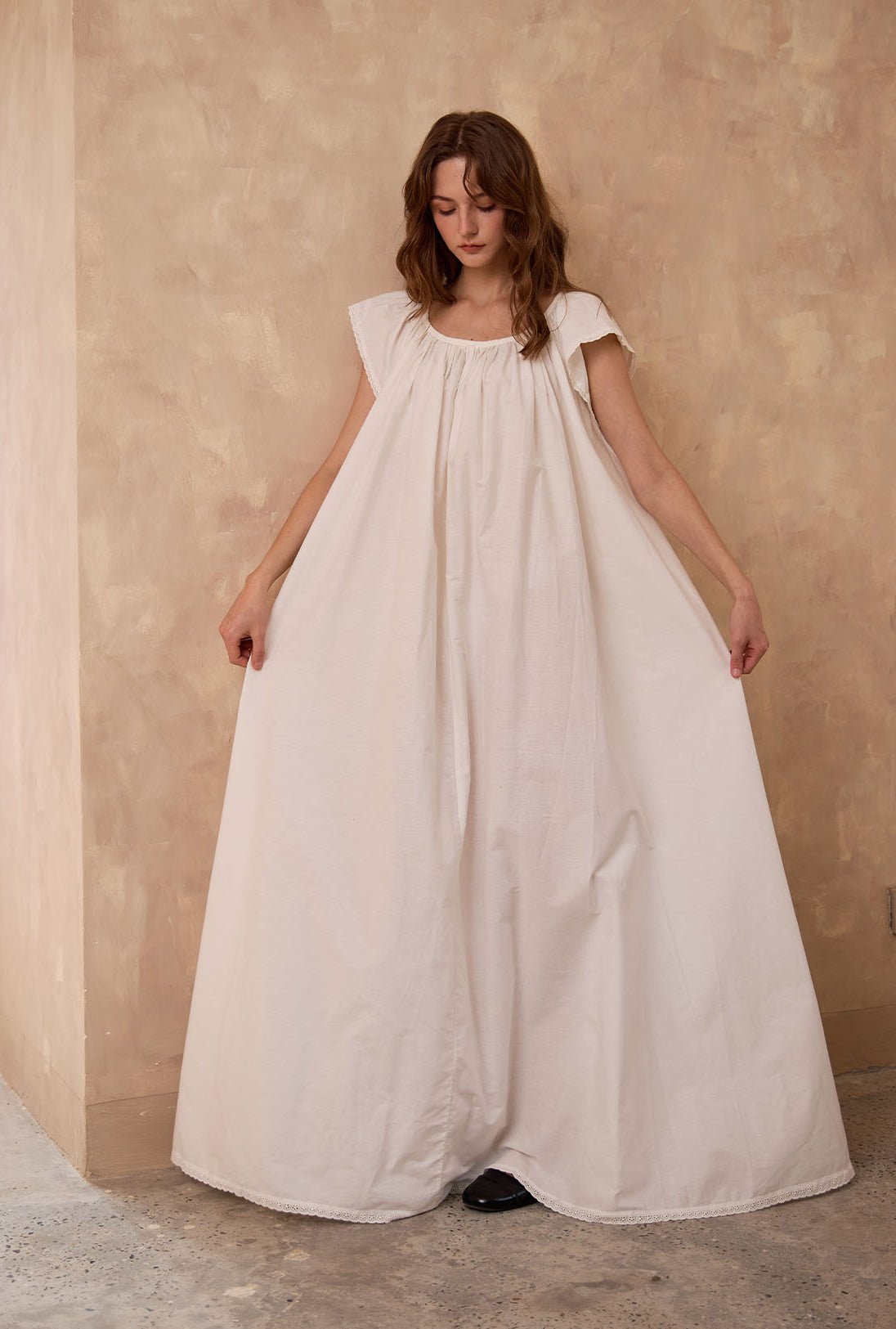 Sueasyretro floor-length ivory Victorian nightgown. Woman holding the voluminous 100% cotton skirt with lace hemline.