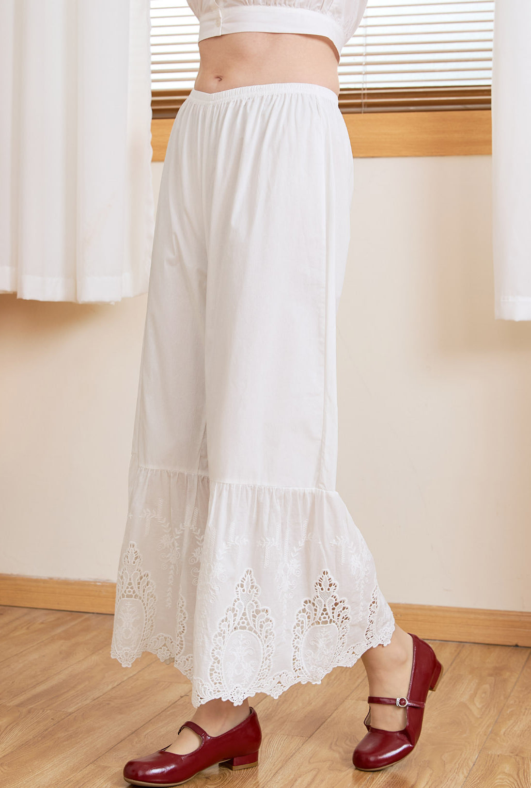 Side profile view of a model in Ivory Sueasyretro cotton lace bloomers, showing wide-leg lace hems.