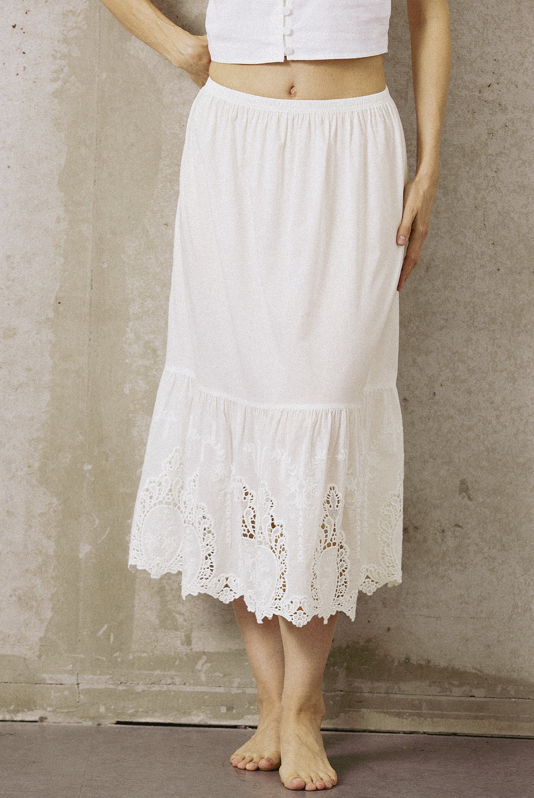 A woman wearing a white anti-static cotton underskirt for dresses, featuring a comfortable elastic waistband and elegant lace detailing.