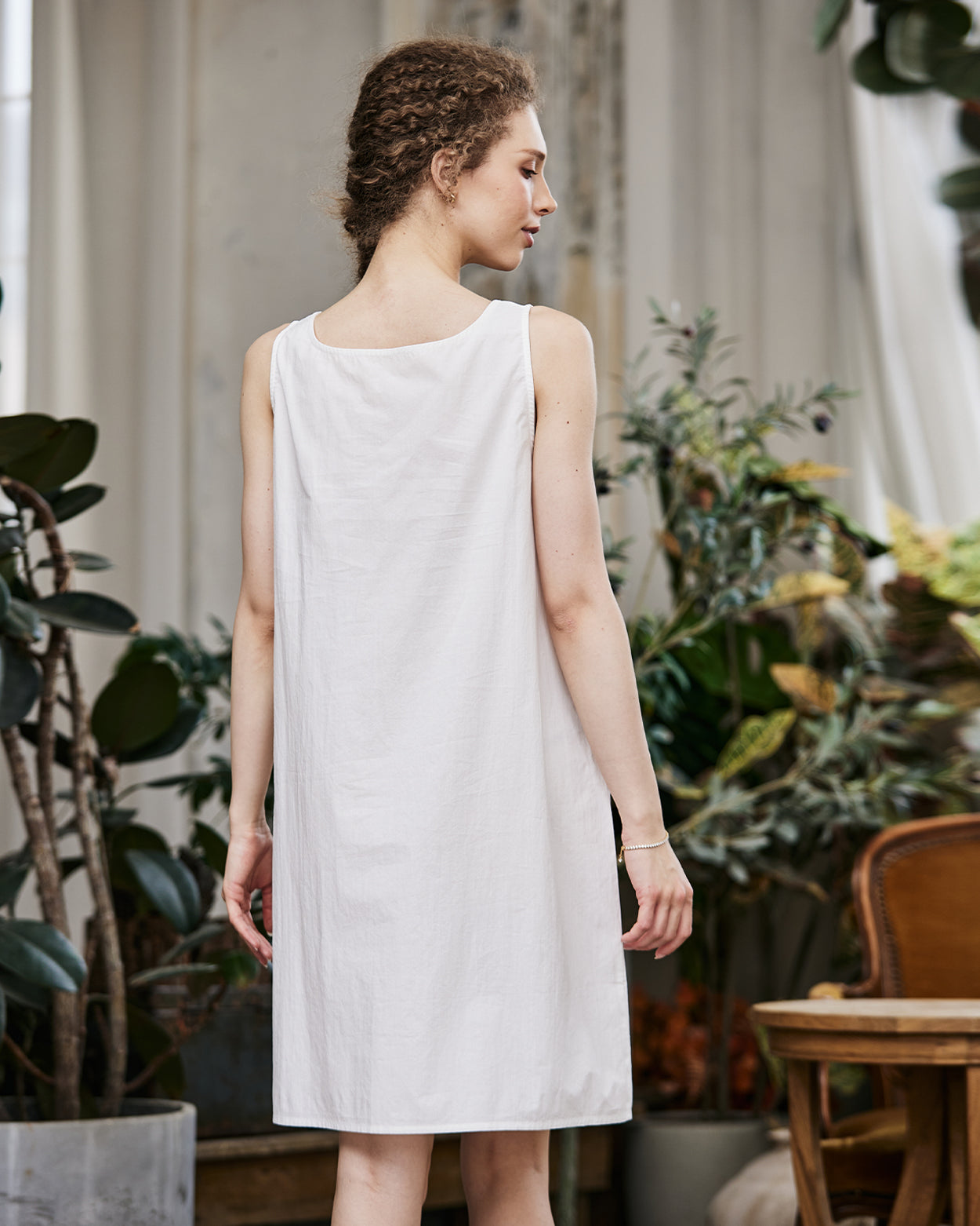 Women's white cotton full slip with wide straps, showing modesty panel and knee-length design - back view