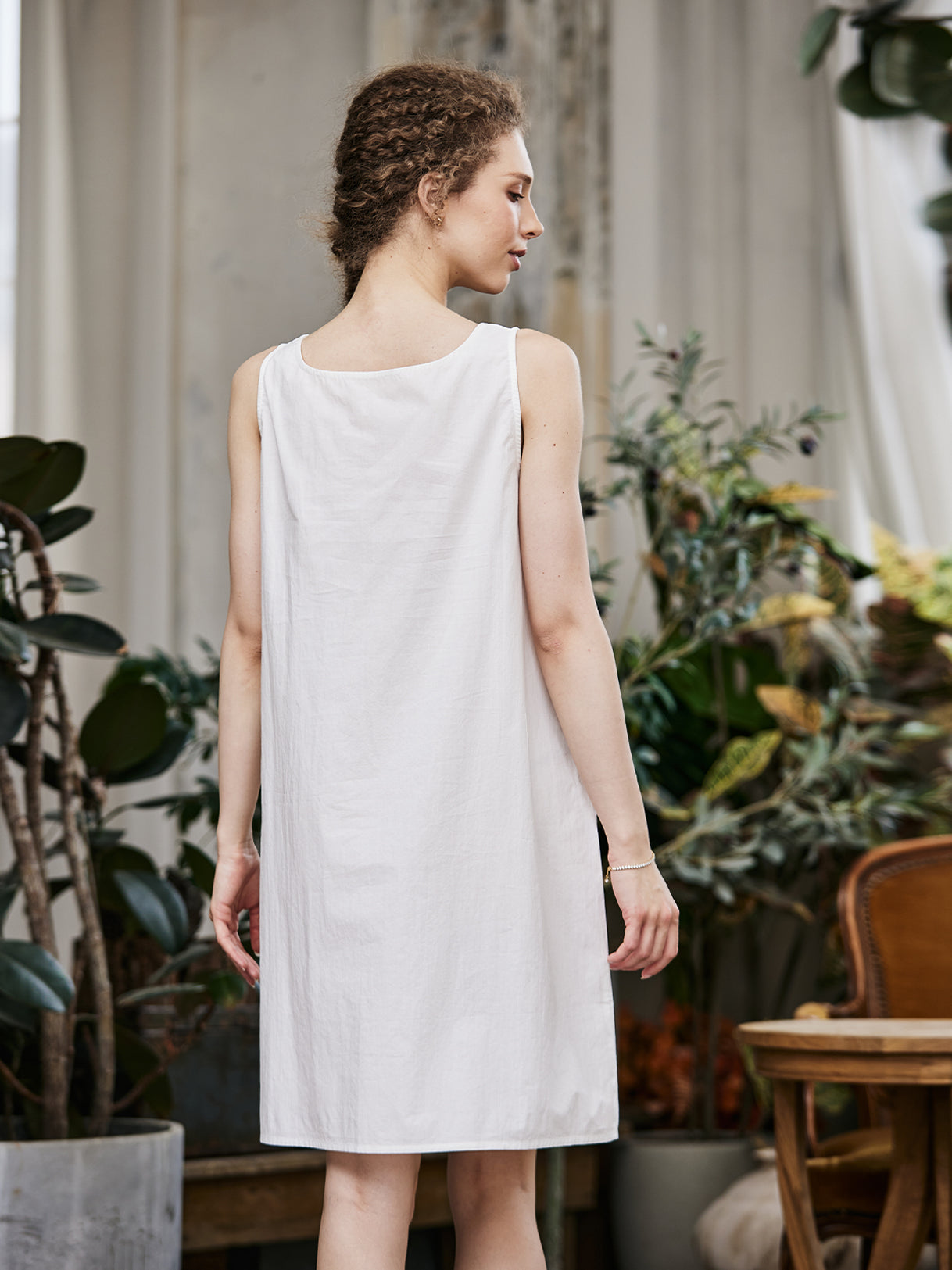 Women's white cotton full slip with wide straps, showing modesty panel and knee-length design - back view