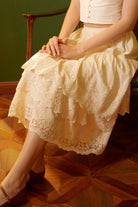 Close-up of a seated woman wearing a breathable cotton skirt extender, showcasing the feminine drape and intricate details of the tiered lace trim.