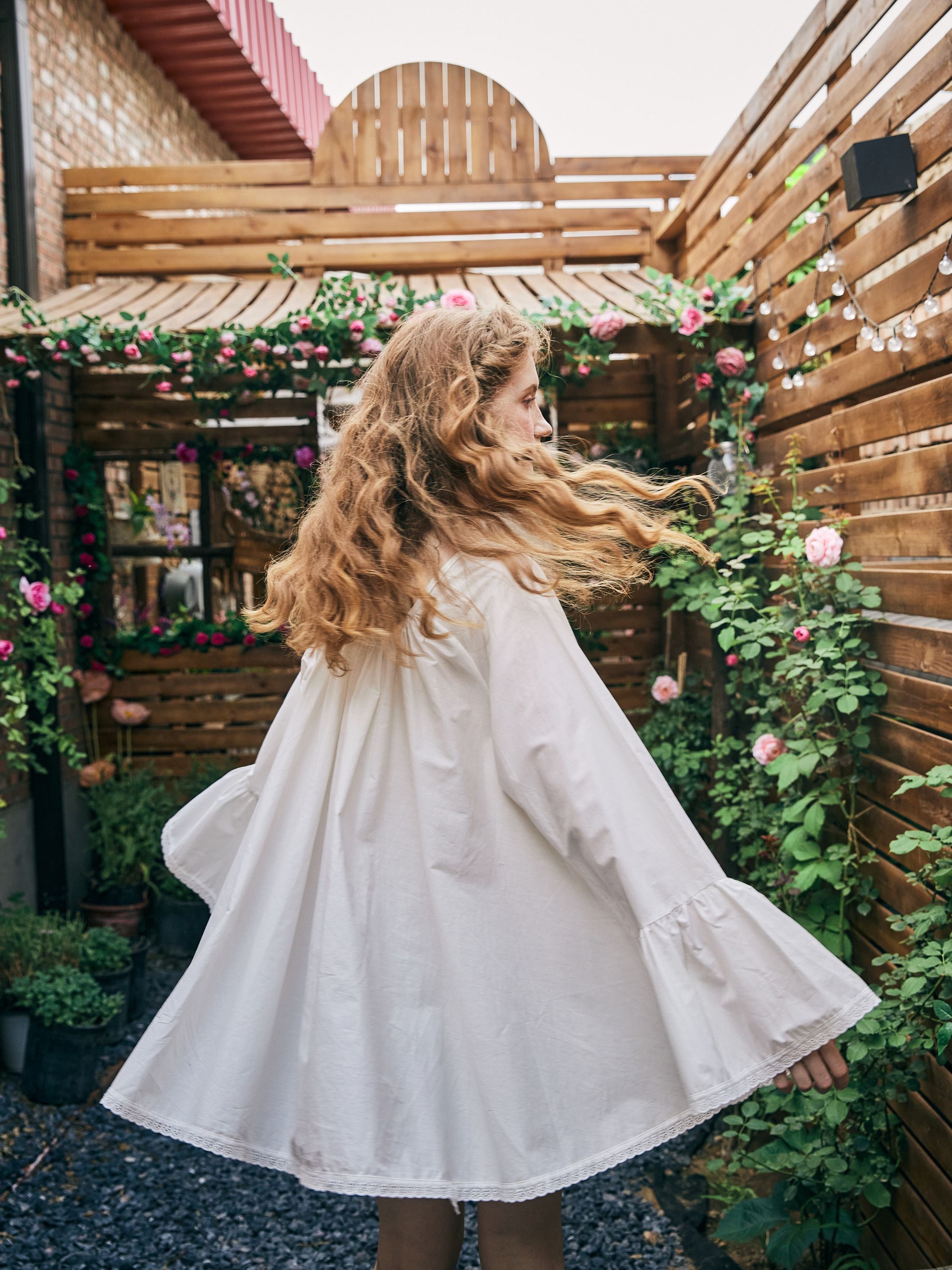 Back view of a flowy, oversized Victorian cotton nightgown in white, showing the comfortable fit and vintage-inspired bell sleeves in motion.