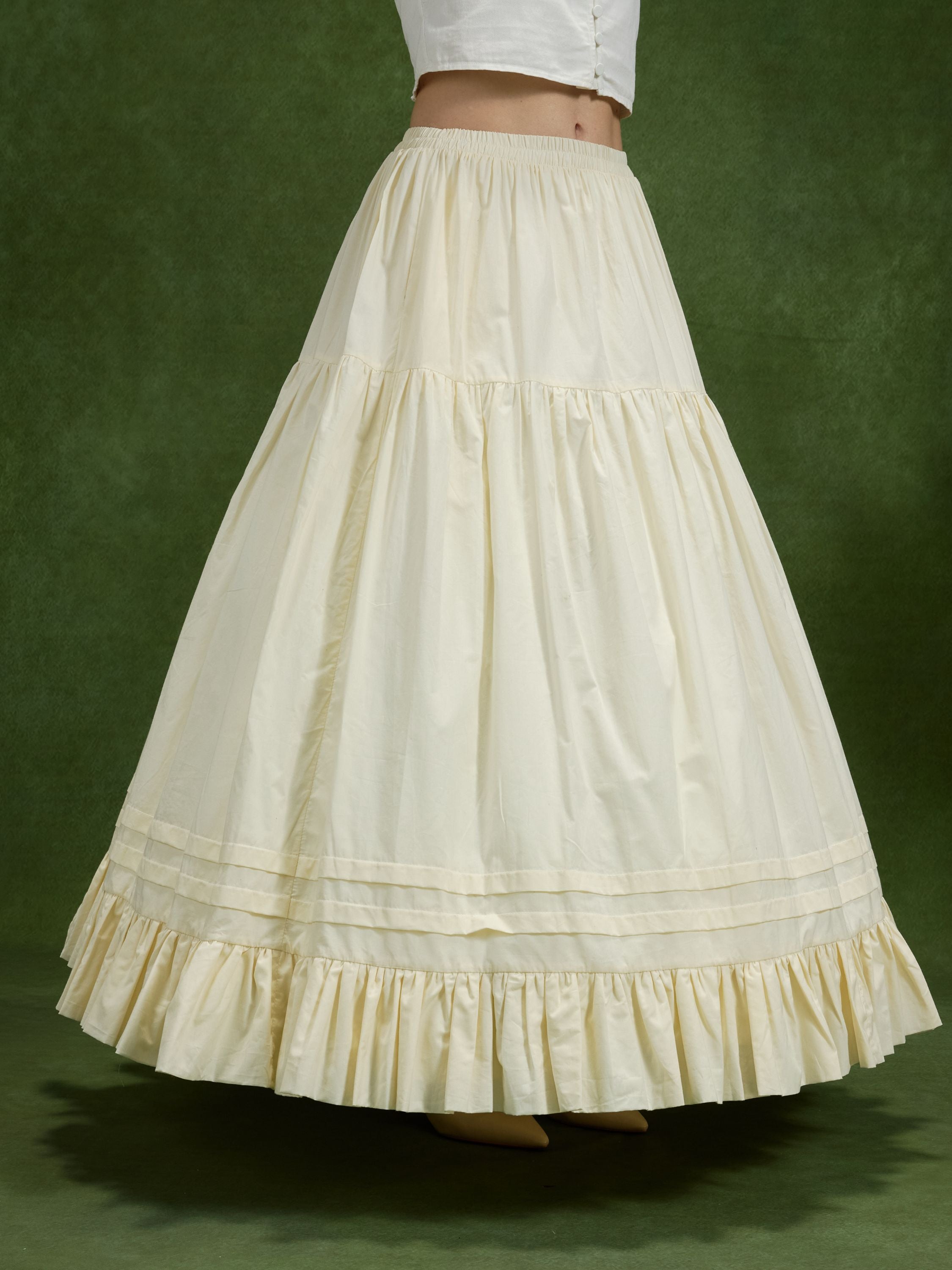 Full-length side view of a woman wearing a voluminous cream tiered cotton petticoat, its structured ball gown shape supported underneath by an ivory 4-hoop crinoline underskirt for historical cosplay dress shaping.