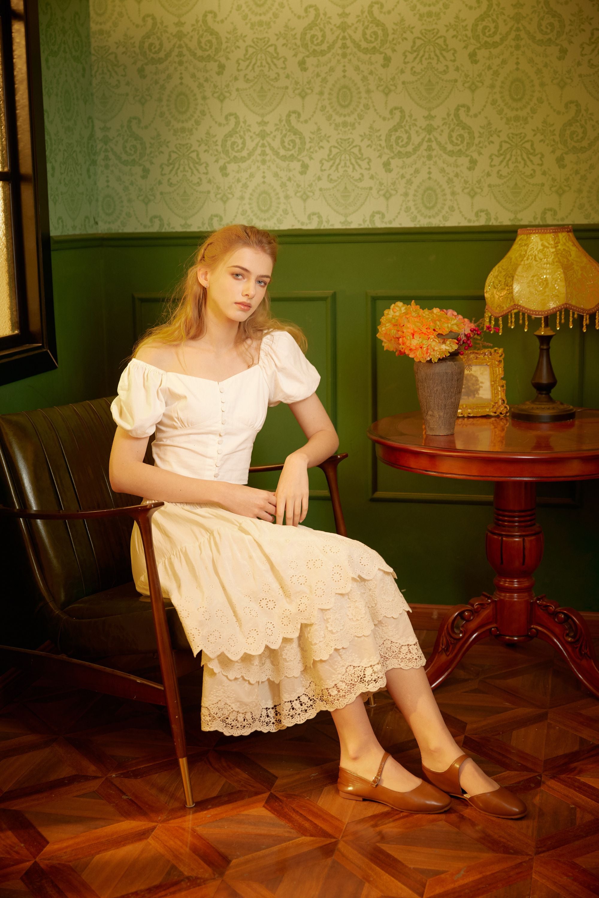 Woman sitting in a vintage room wearing a layered cotton petticoat styled as an elegant skirt with a white top.