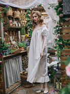 Full length view of a flowing white cotton nightgown for women, featuring breathable fabric, puff sleeves, and a ruffled hem.