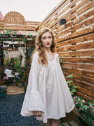 Woman wearing a handmade white 100% pure cotton Victorian nightdress with an elegant neckline and a comfortable oversized fit.