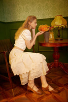 Side view of a seated woman wearing a soft, 100% cotton layered petticoat, highlighting the 3-tier lace embroidery at the hem.