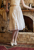 Close-up of a pure white cotton half slip, highlighting gentle waist pleats and a delicate scalloped embroidery hem.