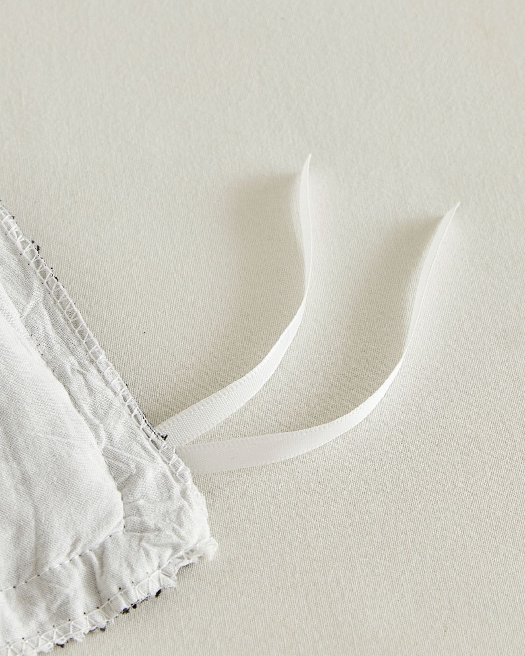 Corner ties detail inside white cotton duvet cover with black ruffle edge to secure comforter