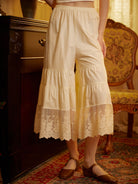 Waist-down view of cream Sueasyretro bloomer pants. These tiered cotton bloomers feature a sheer floral lace hem.