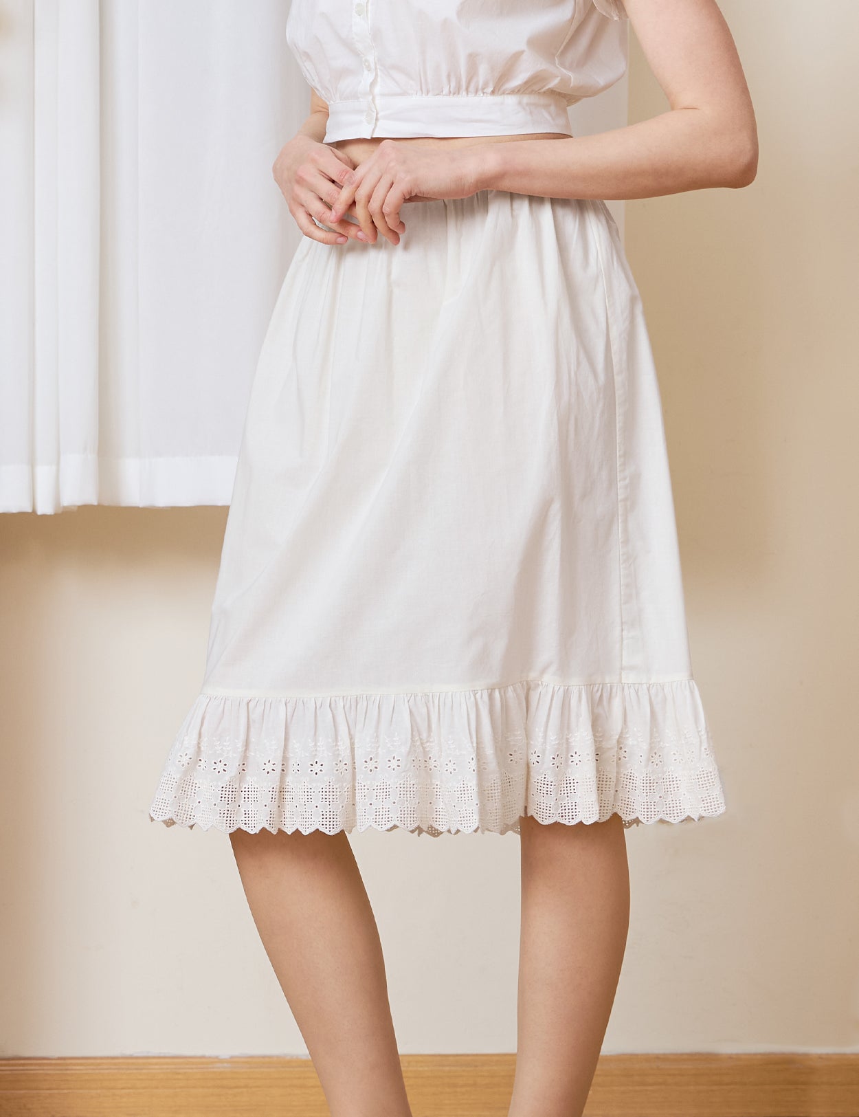 Ivory cotton petticoat with intricate floral lace trim and embroidered ruffle hem, knee-length.