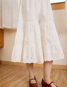 Close-up of the delicate floral eyelet lace hem on these cream cotton bloomers, showing exquisite vintage craftsmanship.