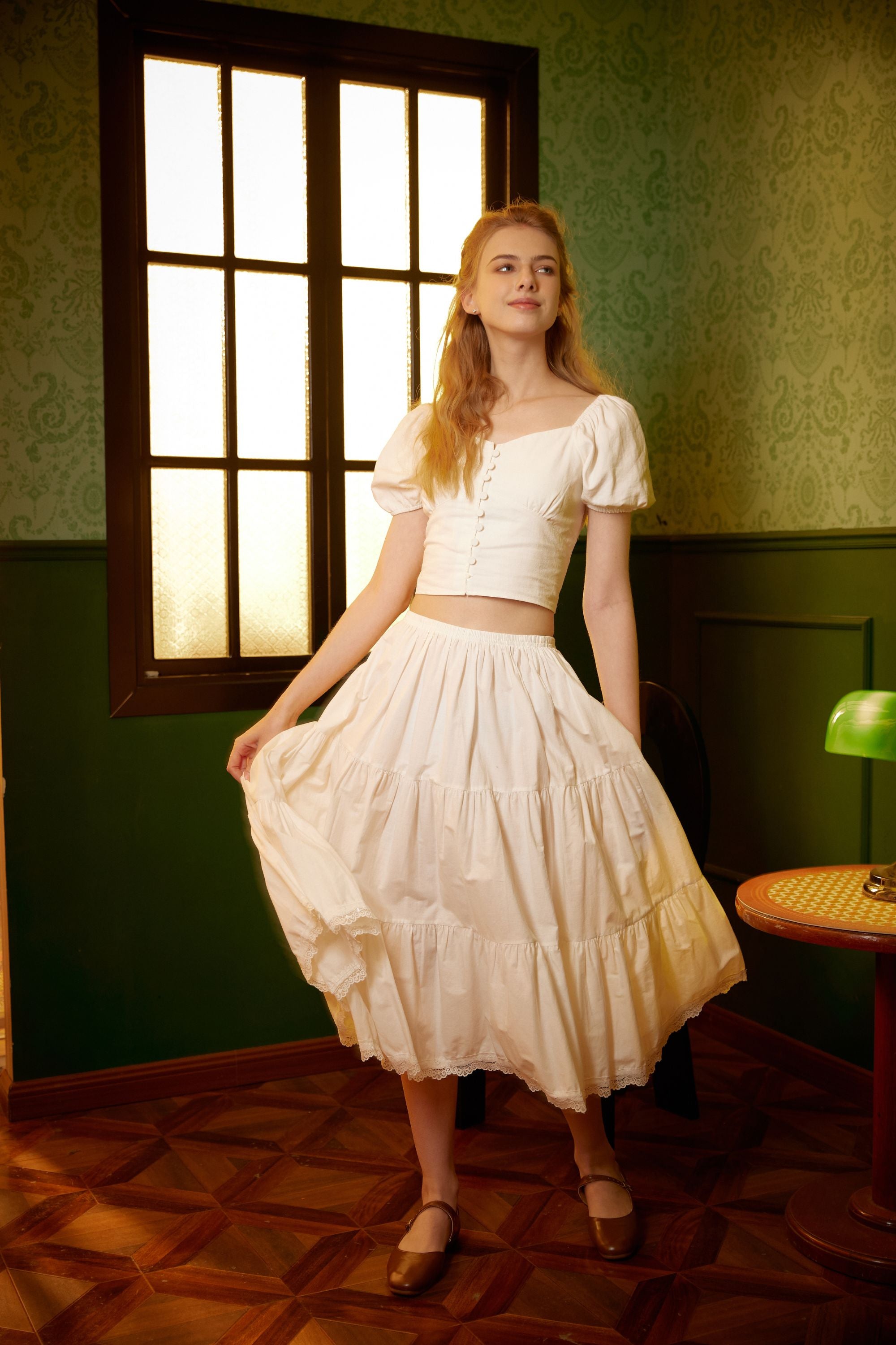 Woman in a vintage room twirling a long ivory cotton Victorian underskirt, demonstrating the full A-line drape and retro style.