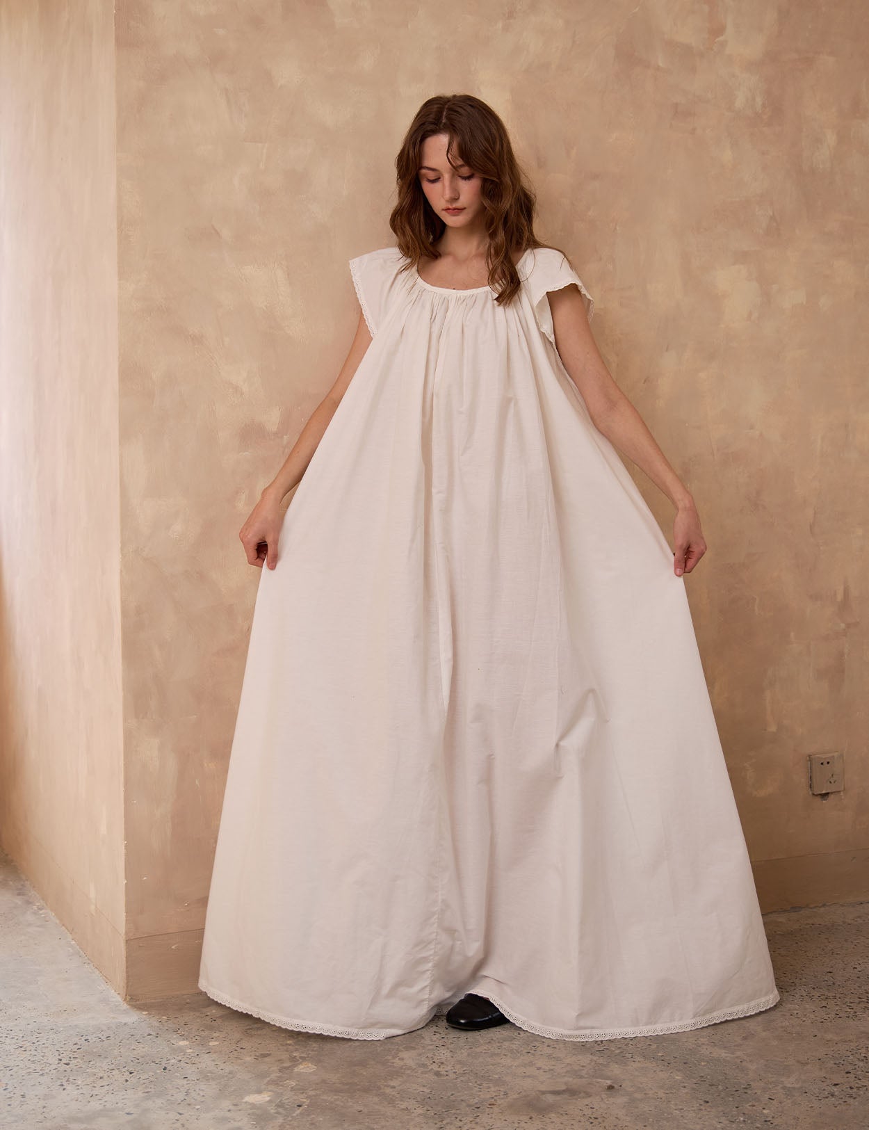 Sueasyretro floor-length ivory Victorian nightgown. Woman holding the voluminous 100% cotton skirt with lace hemline.