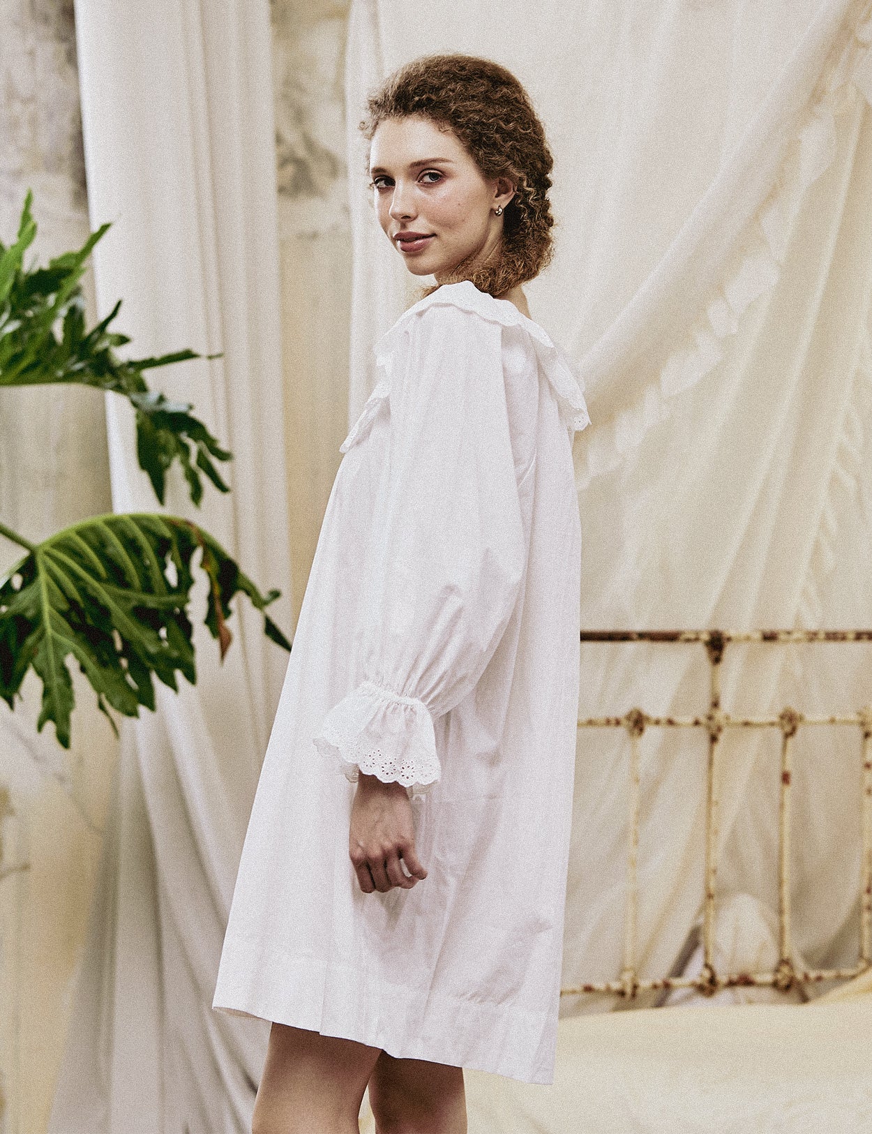 Side view of an oversized long sleeve peasant nightgown with elasticated ruffle cuffs and flowing embroidered hem.