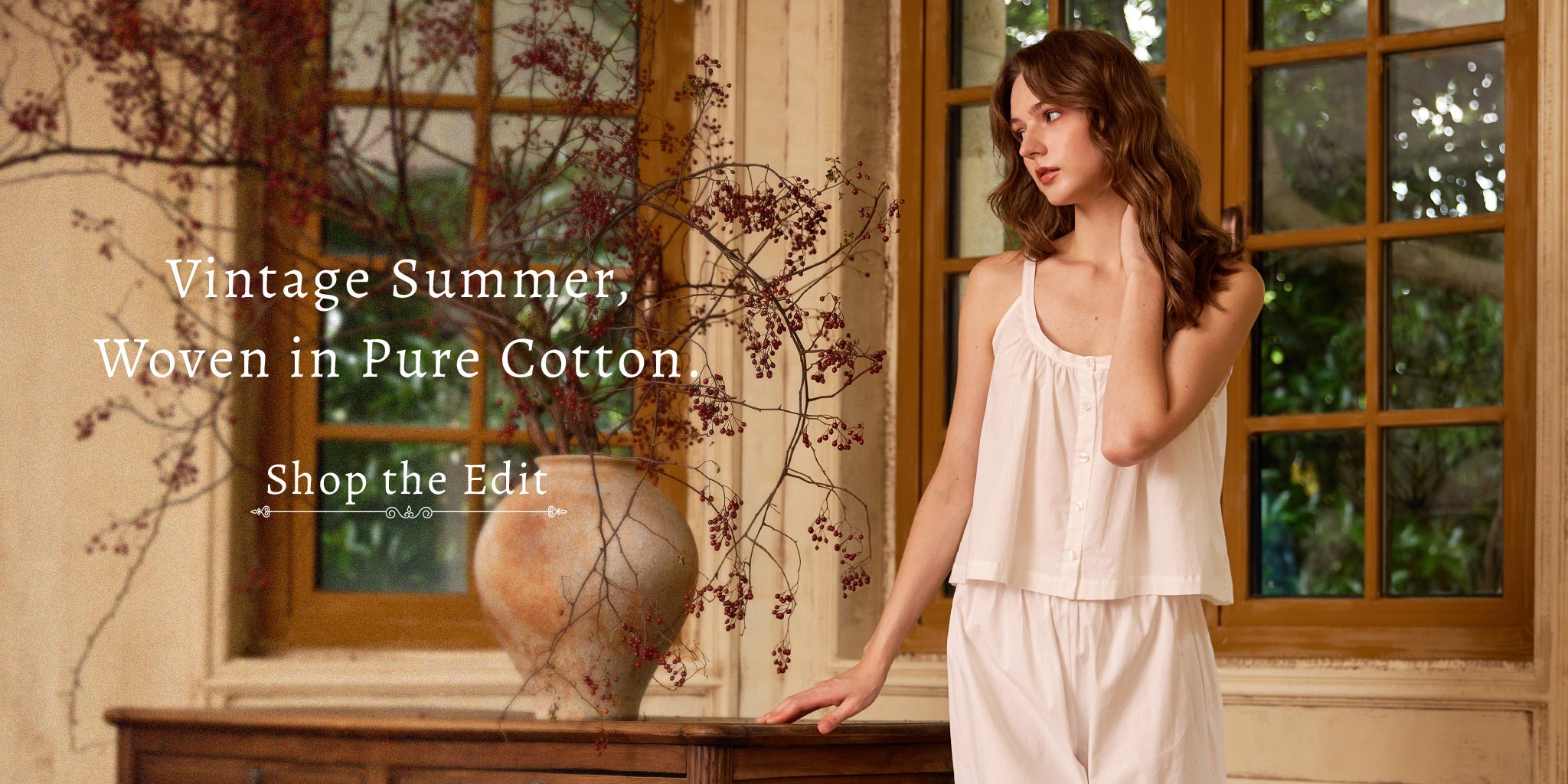 Sueasyretro desktop banner featuring a woman modeling white vintage pure cotton loungewear next to a rustic vase. Text reads: 'Vintage Summer, Woven in Pure Cotton. Shop the Edit.