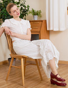 Model sits in wooden chair wearing Ivory Sueasyretro vintage bloomer pants with delicate lace details.