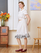 Sueasyretro Cotton Skirt Extender: full body side view of white slip with black floral ruffle hem and vintage styling.