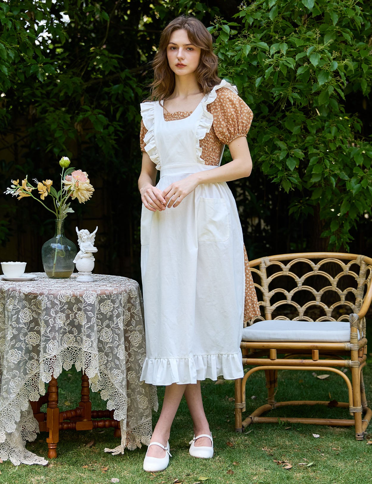 Woman in ivory Victorian cotton pinafore apron standing in garden setting