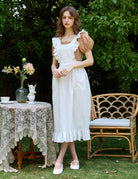 Woman in ivory Victorian cotton pinafore apron standing in garden setting
