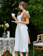 Woman wearing Victorian cotton pinafore apron at afternoon tea party
