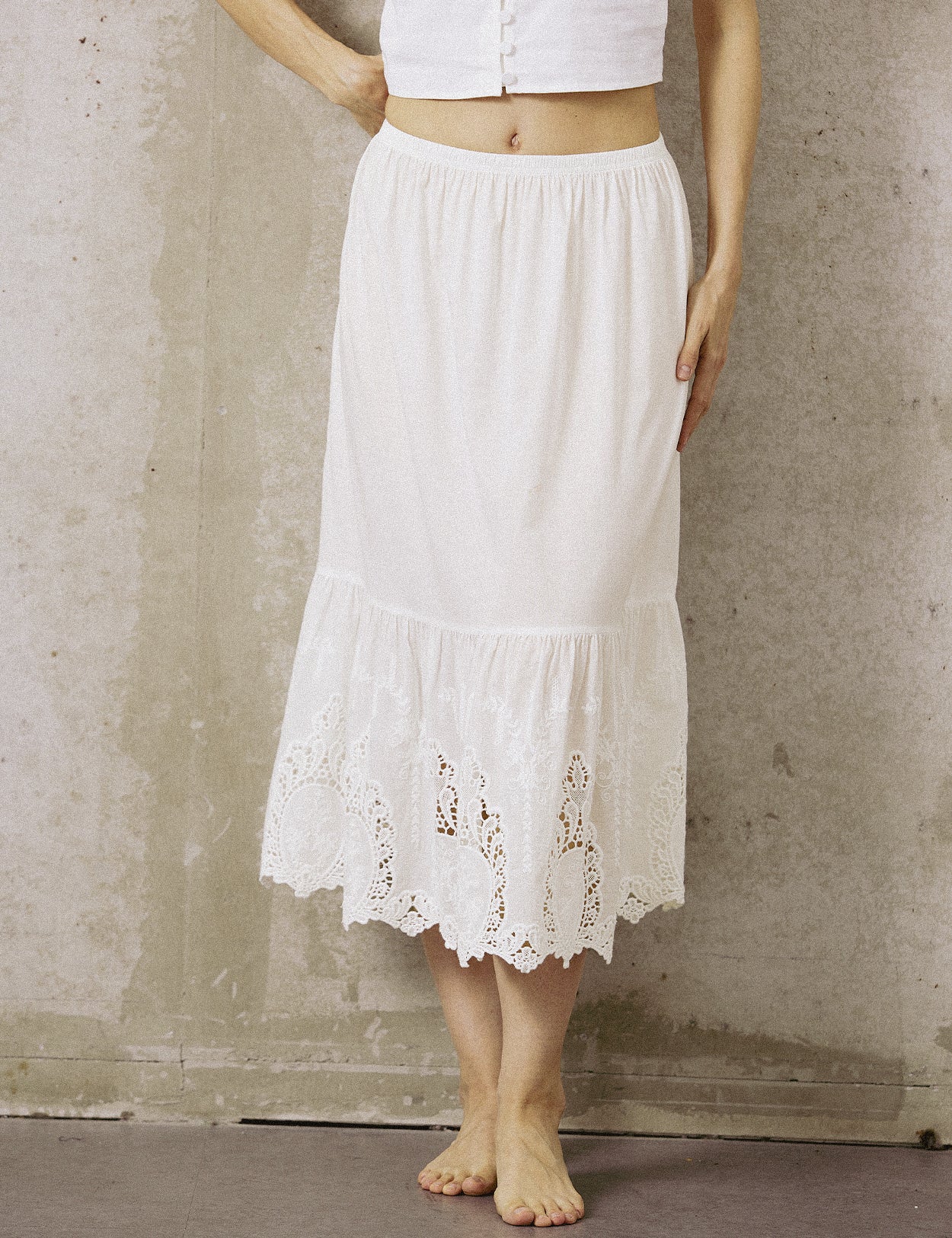 A woman wearing a white anti-static cotton underskirt for dresses, featuring a comfortable elastic waistband and elegant lace detailing.