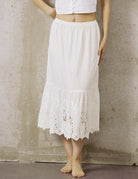 A woman wearing a white anti-static cotton underskirt for dresses, featuring a comfortable elastic waistband and elegant lace detailing.