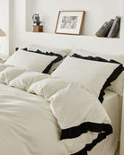 Side view close up of vintage white washed cotton bedding set featuring ruffle pillows and duvet cover with black contrast trim