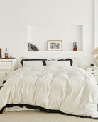 Full view of vintage white washed cotton duvet cover set with black ruffle trim styled in a minimalist bedroom