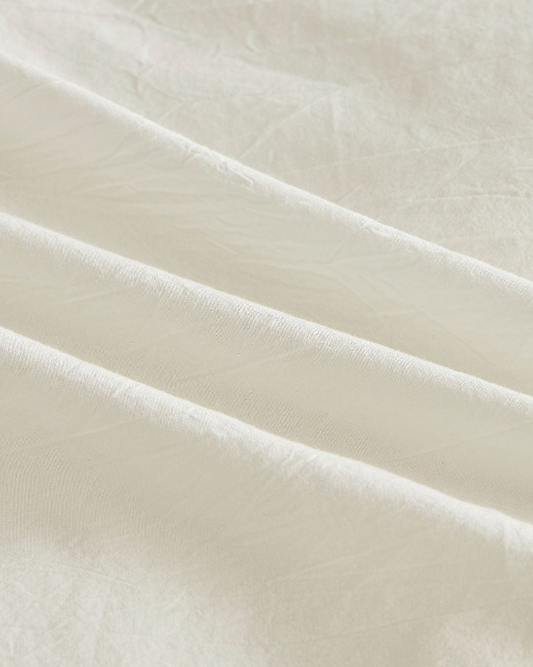 Close up texture view of soft white washed cotton fabric showing natural wrinkles and breathable quality