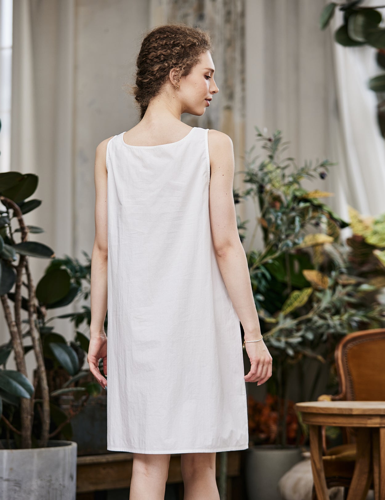 Women's white cotton full slip with wide straps, showing modesty panel and knee-length design - back view