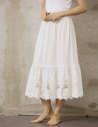 Close-up front view of a white 100% cotton mid-calf half slip with intricate embroidery lace trim at the hem.