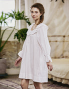 Side view of an oversized long sleeve peasant nightgown with elasticated ruffle cuffs and flowing embroidered hem.